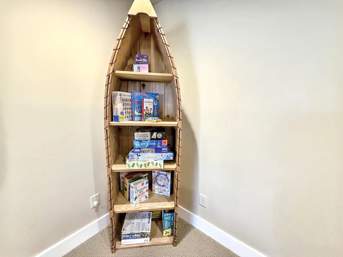 A playful corner with a boat-shaped bookshelf filled with colorful board games. The space is designed for family fun, group activities, and creative game nights.