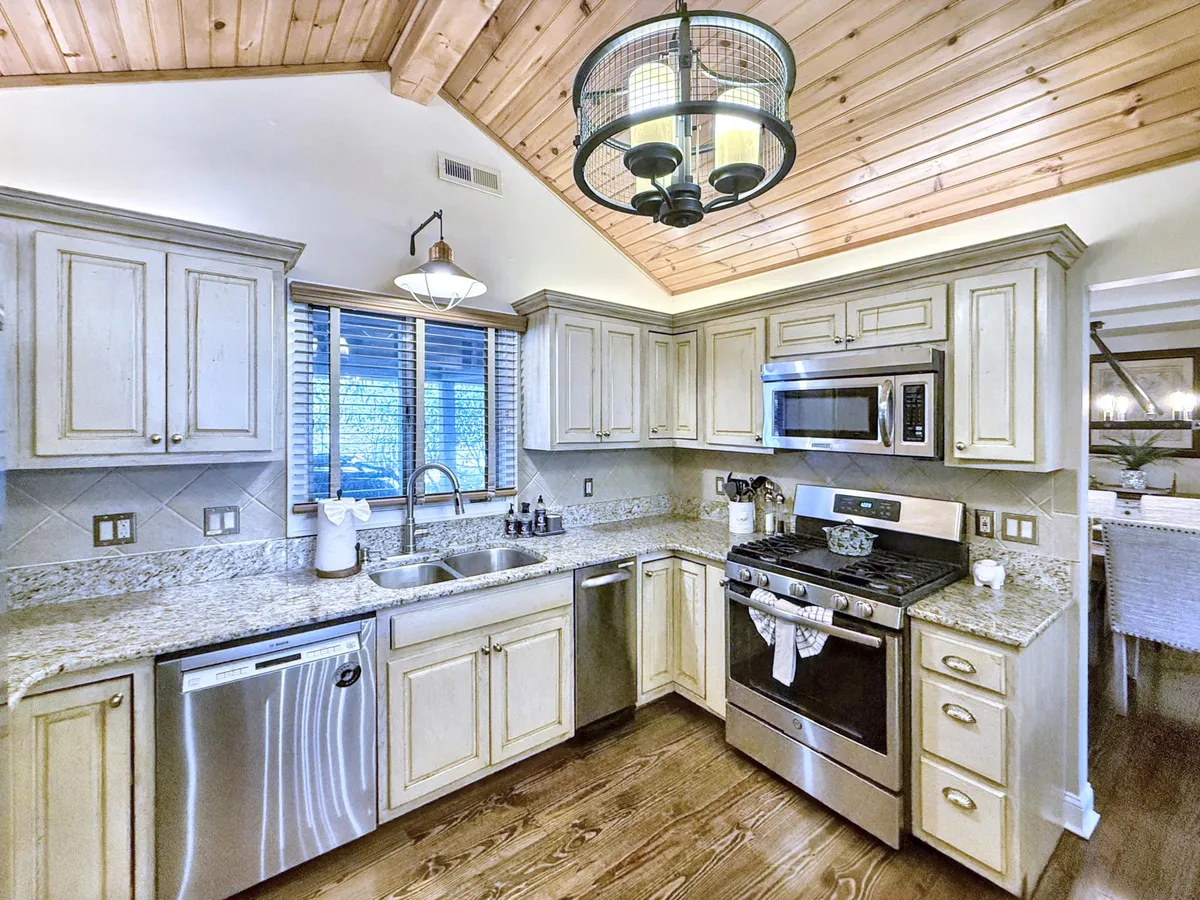 A bright, well-equipped kitchen with granite countertops, stainless steel appliances, overhead lighting, and wooden ceiling details. The space is stylish and functional, inviting residents and guests to enjoy cooking and entertaining.