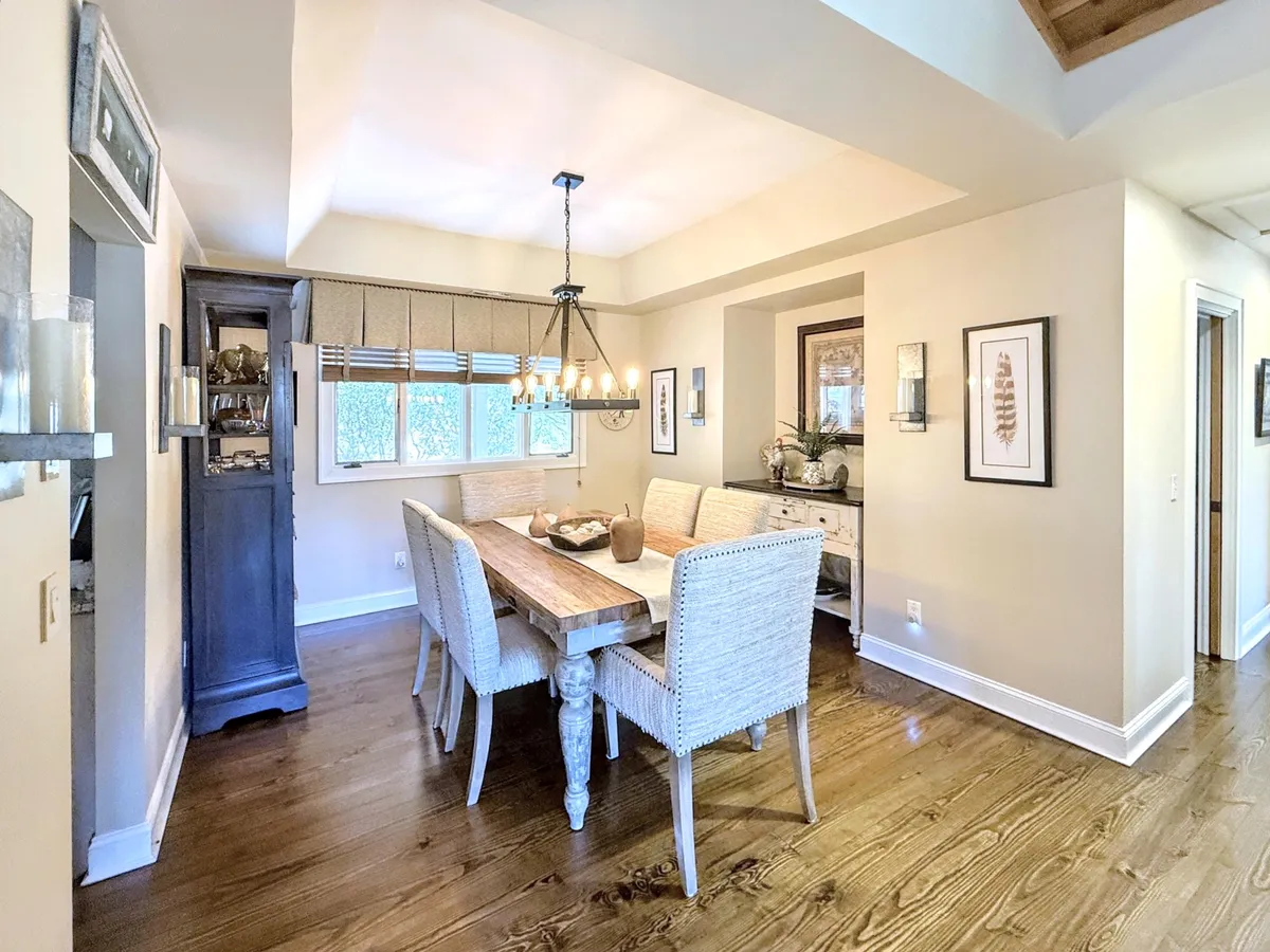 A spacious dining area with a large table, a stylish chandelier overhead, and artwork on the walls. The arrangement creates an inviting setting for group activities like game nights or shared meals.