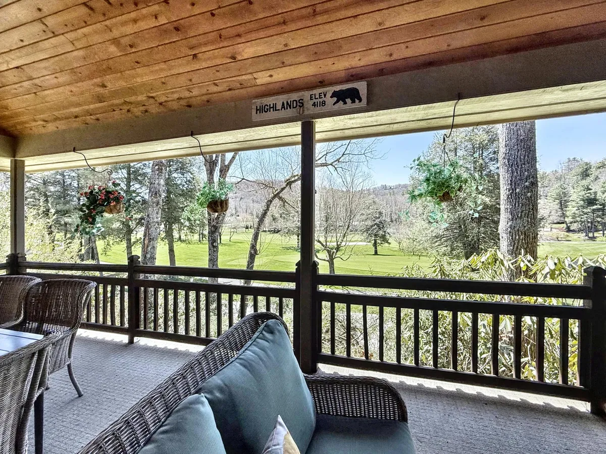 The image shows the exterior of a single-family house nestled in lush greenery, with inviting comfortable seating on a spacious porch surrounded by hanging plants. The serene landscape stretches beyond, perfect for relaxing, enjoying morning coffee, or gathering with friends, while local wildlife and sunset views add to the tranquil atmosphere.